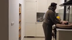 Baby verschoond onder de afzuigkap Vader verschoont een baby op een fornuis onder een afzuigkap in een keuken.