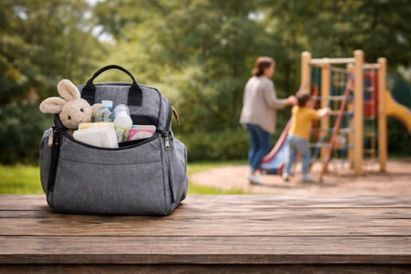 Luiertas op een tafel met speeltuin op de achtergrond.