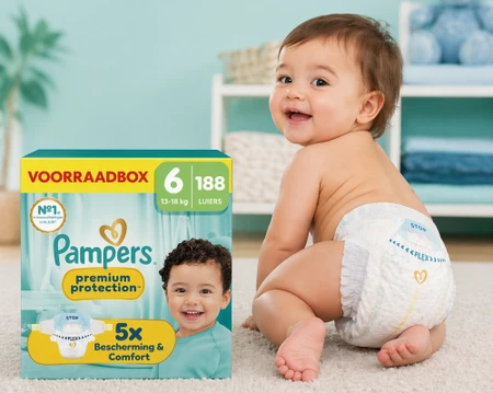 Baby met Pampers-luier naast Pampers voorraadbox in woonkamer.
