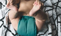 Baby ligt met een een groene wasbare luier op een dekentje