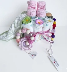 Maminobaby luiertaart voor meisjes met speenkoord en slabbetje Roze luiertaart met babyslofjes, bloemen, speenkoord, bijtring en slabbetje op witte achtergrond
