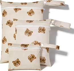 Drie beige wetbags met bruine berenprint, witte ritsen en polsbandjes met drukknopen.
