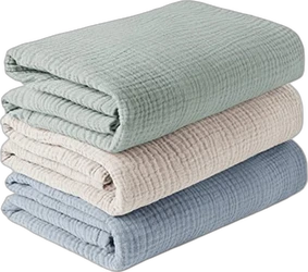 Drie opgevouwen hydrofiele doeken gestapeld in saliegroen beige en blauw met wafelachtige textuur