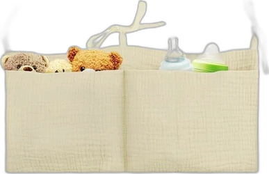 Crème hangende organizer met twee opbergvakken, knuffels, babyfles en doosje erin.