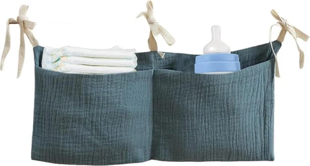Donkergroene stoffen babybedorganizer met striklinten, luiers en babyfles in de vakken