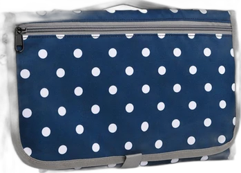Opgevouwen draagbare verschoningsmat in navy blauw met witte stippen, grijze rand en ritsvak.