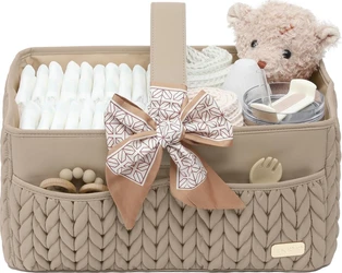 Beige gevlochten luiercaddy met grote strik, gevuld met luiers, knuffelbeer en babyaccessoires