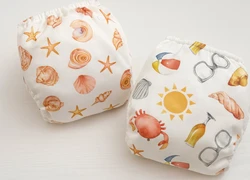 Twee herbruikbare luiers met strandthema print schelpen krab zonnebril en zon in zachte kleuren