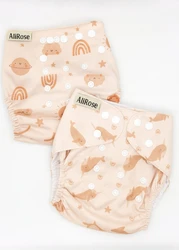 Twee AliRose herbruikbare pocket luiers in zacht perzik met narwal en hemel prints en verstelbare drukknopen