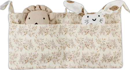 Beige katoenen babybed-opbergtas met klein bruin bloemmotief en twee knuffels zichtbaar