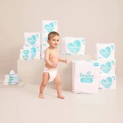 Baby in luiers met stapels Pamperspakken op een lichte achtergrond.