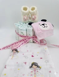 Meisjes luiertaart met opgerolde luiers, witte babyslofjes, roze muts en doek met speelse print